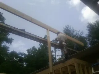 Carpenter setting a ridge beam over a new addition frame — Ice Dam Removal by Roofing Brothers in Manning