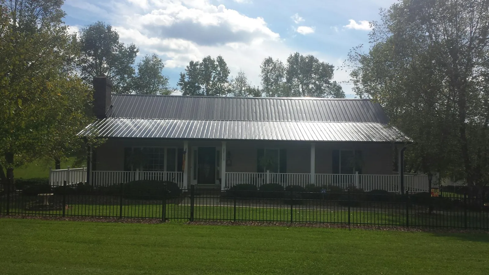 Gray metal roof on a brick ranch with a full width front porch — Gutter Guard Installation work by our crew in Manning